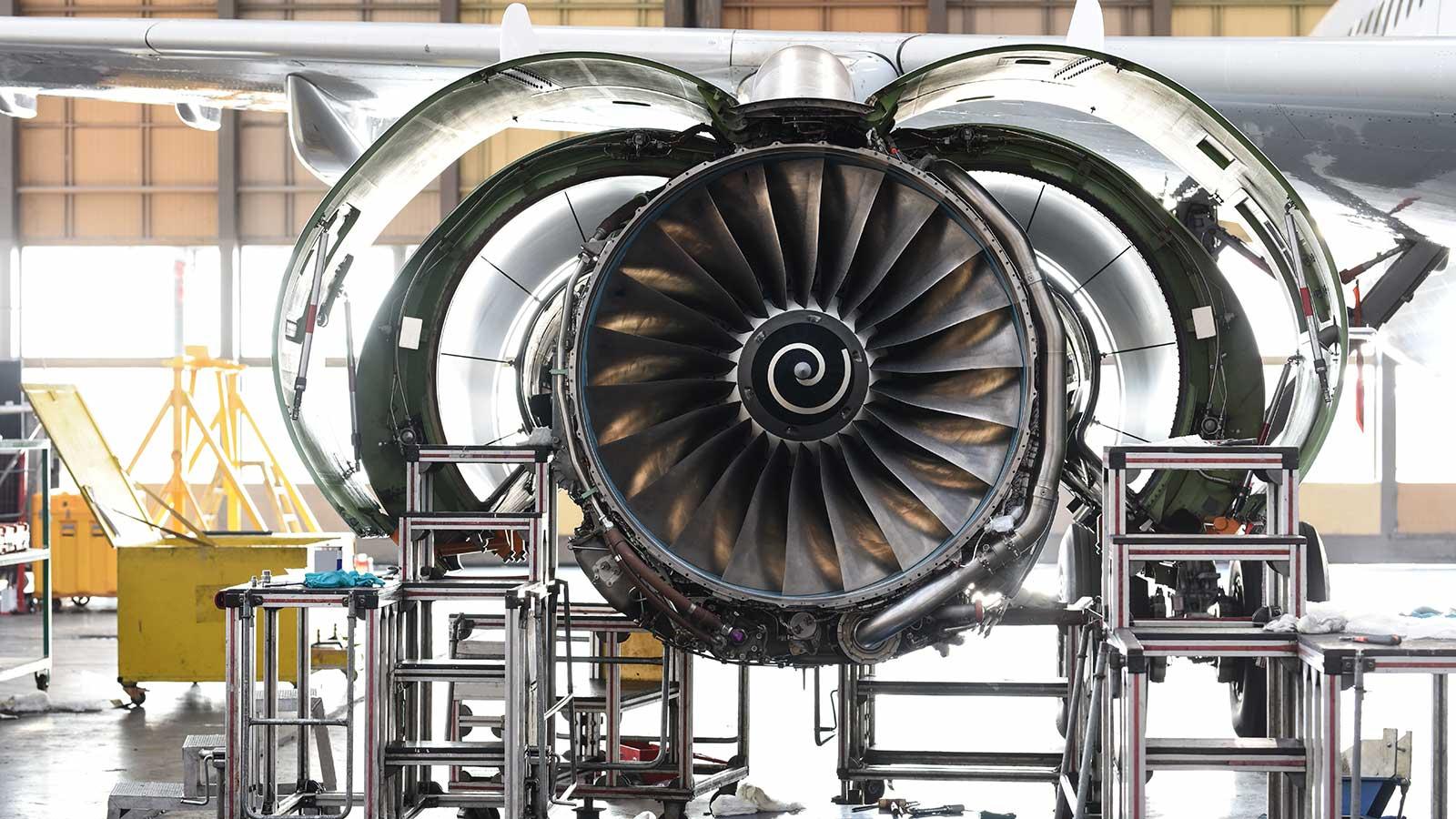 A jet engine being worked on in a large hangar