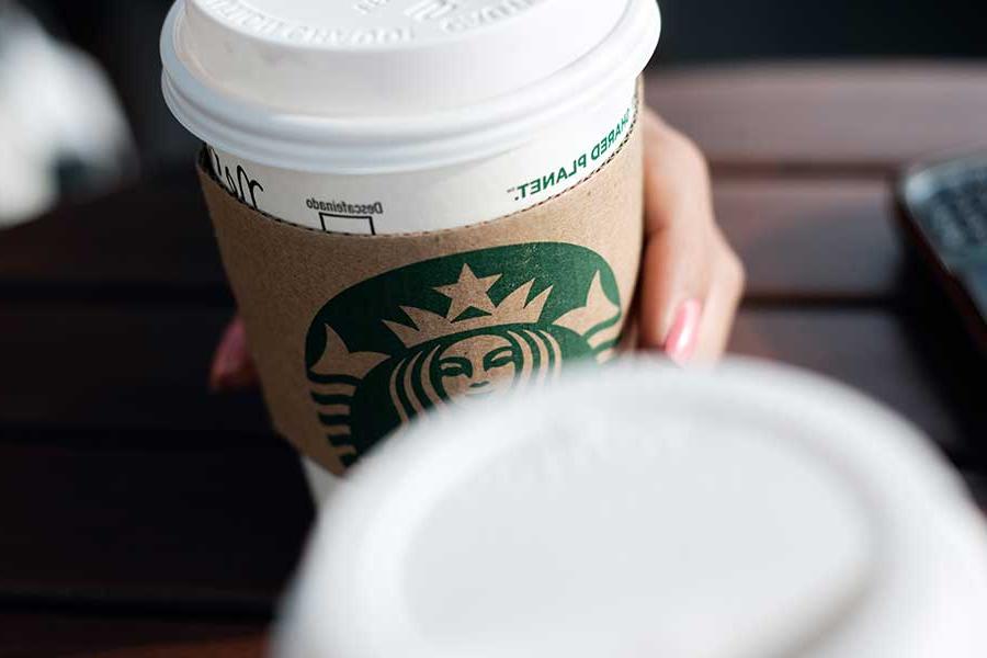 Individual holding a Starbucks coffee cup
